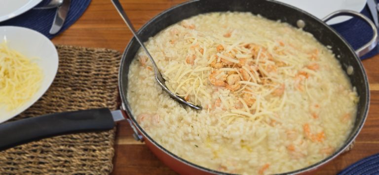 A steaming bowl of creamy shrimp risotto, garnished with plump shrimp, fresh parsley, and a sprinkle of grated Parmesan cheese.