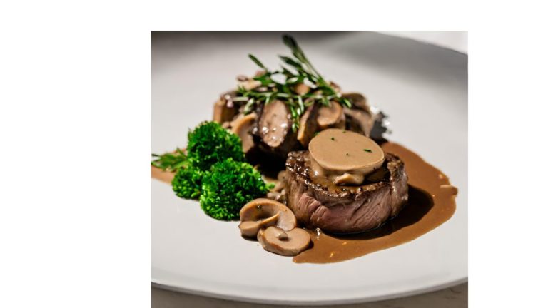 A picture of a Filé ao Molho Madeira dish. The dish consists of filet mignon medallions that are topped with a Madeira wine sauce and mushrooms. The medallions are surrounded by parsley.