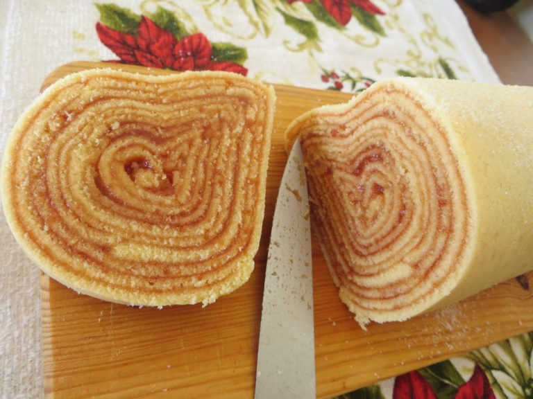 A close-up of sliced Bolo de Rolo showcasing the vibrant guava filling swirled within the delicate sponge layers.