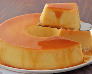 A close-up view of a slice of Brazilian Condensed Milk Flan (Pudim de Leite Condensado) on a serving plate.