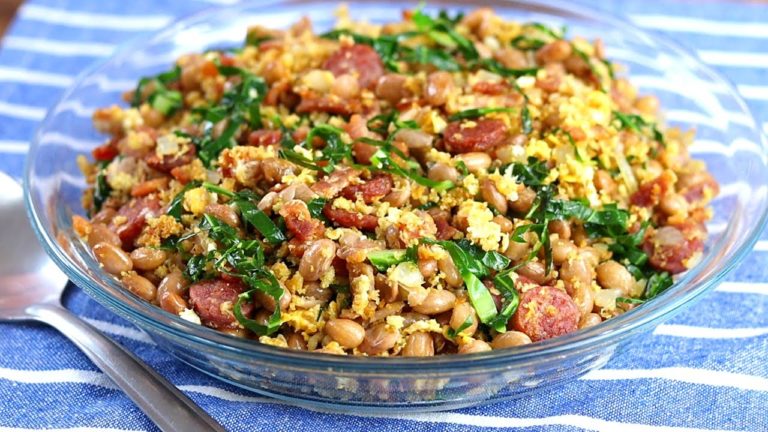 A vibrant plate of Feijão Tropeiro showcasing a medley of beans, bacon, sausage, cassava flour, and fried eggs.