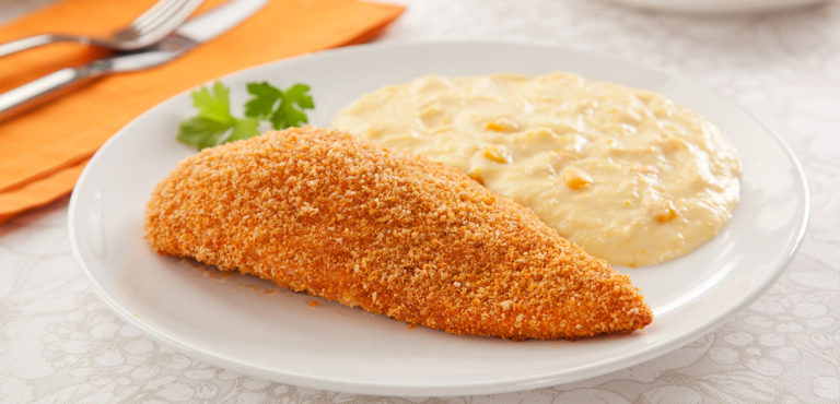 A golden-brown chicken breast, perfectly coated in panko crumbs, sits nestled next to a bowl of creamy corn delight.