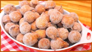 A close-up shot of fluffy golden brown beignets dusted with cinnamon sugar, nestled on a rustic wooden table.