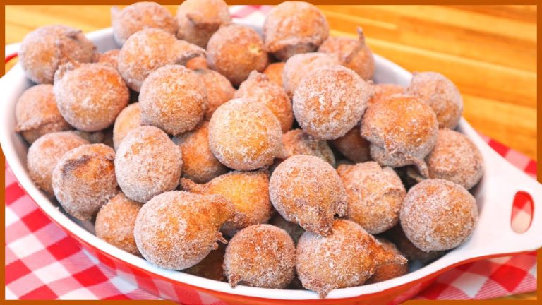 A close-up shot of fluffy golden brown beignets dusted with cinnamon sugar, nestled on a rustic wooden table.