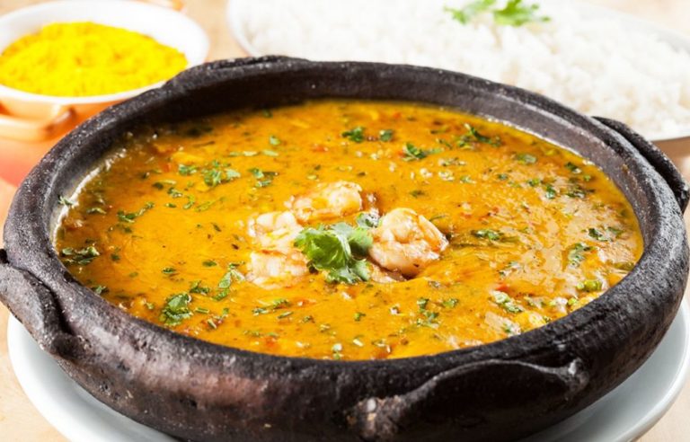 A steaming bowl of Shrimp Bobó garnished with fresh cilantro, served alongside fluffy white rice.