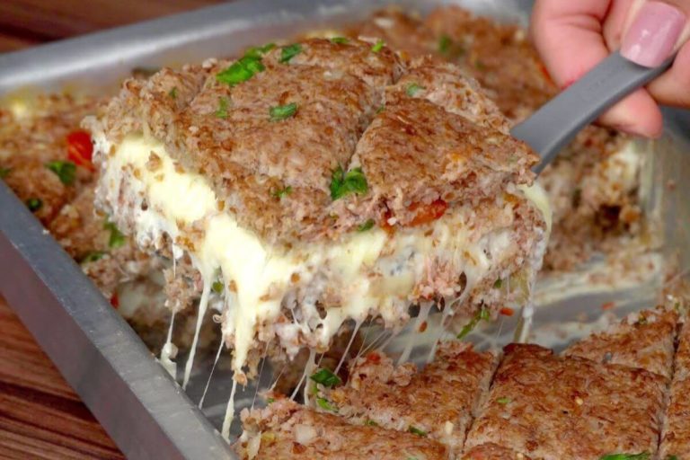 A close-up view of a sliced Stuffed Baked Kibbeh, revealing the creamy cheese filling.